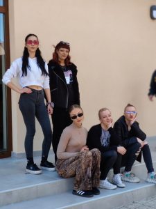 Pet učenica od kojih tri sjede na stepenicama, a ostale stoje iza njih.