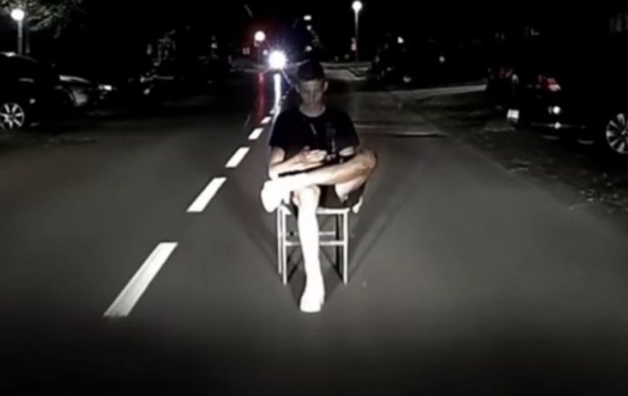 mladić sjedi na sred ceste