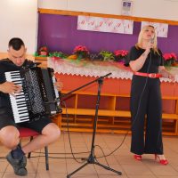 Muška osoba svira harmoniku, dok ženska osoba pjeva.