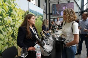 Dvije ženske osobe pričaju za stolom na kojem se nalazi vino u bocama