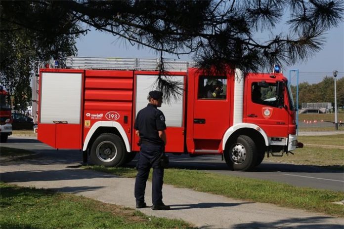 vatrogasno vozilo ispred kojeg stoji policajac