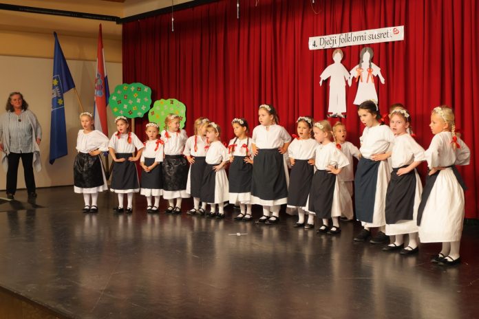 Djeca folkloraši stoje na pozornici obučeni u narodne nošnje
