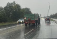 Traktor na cesti, auti se kreću pokraj njega