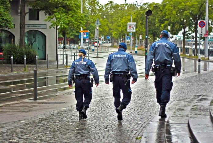 Na ilustraciji su dva njemačka muška policajca i jedna ženska policajka. Izgledaju kao da nekoga traže jer su u hodu na ulici.