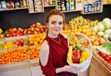 djevojka u crvenoj haljini u dućanu u rukama drži košaru punu voća