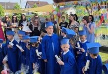 Na slici su 23 djece iz vrtića u plavim odorama u dvorištu na završnoj priredbi